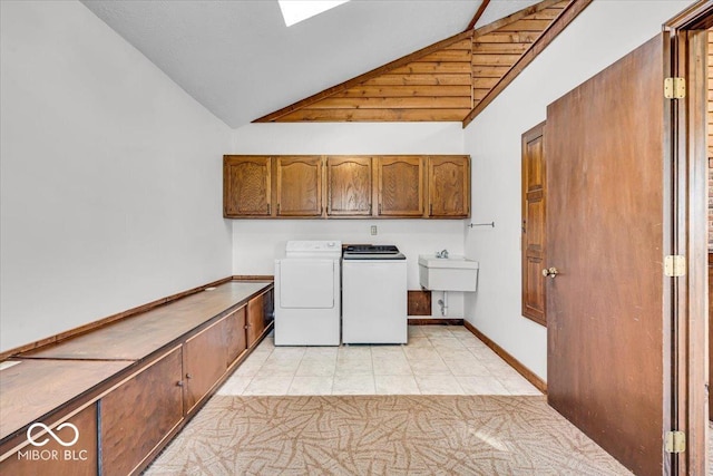 washroom featuring independent washer and dryer, a sink, cabinet space, light tile patterned flooring, and baseboards