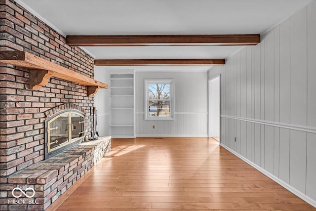 unfurnished living room featuring beamed ceiling, a fireplace, and hardwood / wood-style floors