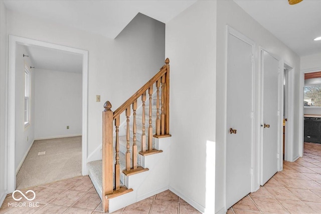 stairs with tile patterned floors, baseboards, and carpet