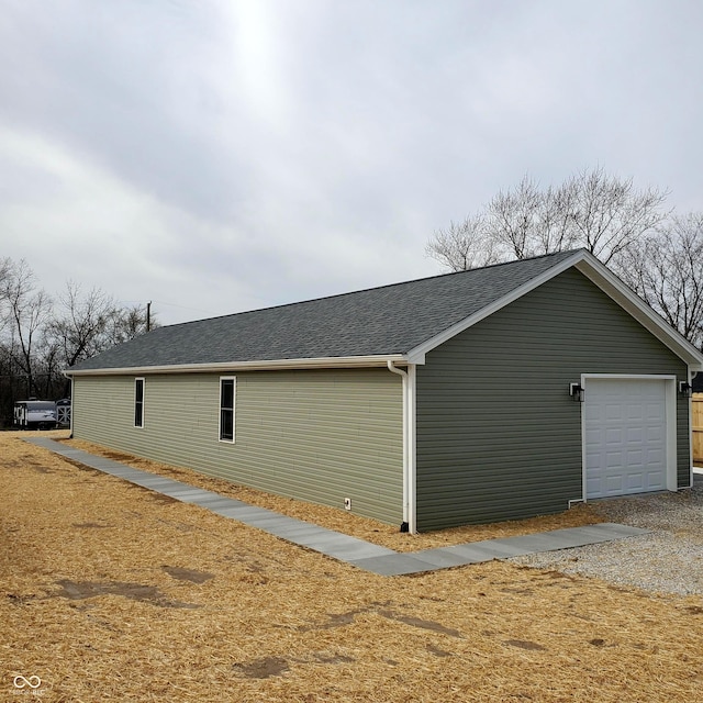 view of home's exterior featuring roof with shingles and driveway