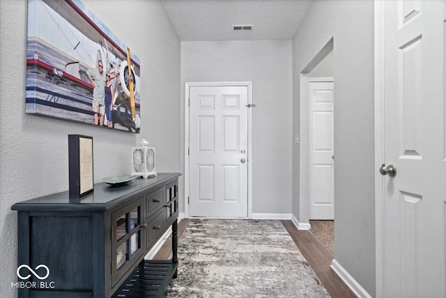 corridor with dark hardwood / wood-style floors and a textured ceiling