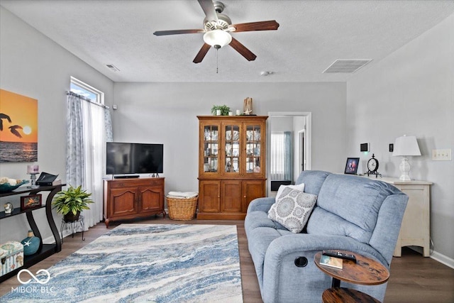 living room featuring hardwood / wood-style flooring, a textured ceiling, and ceiling fan