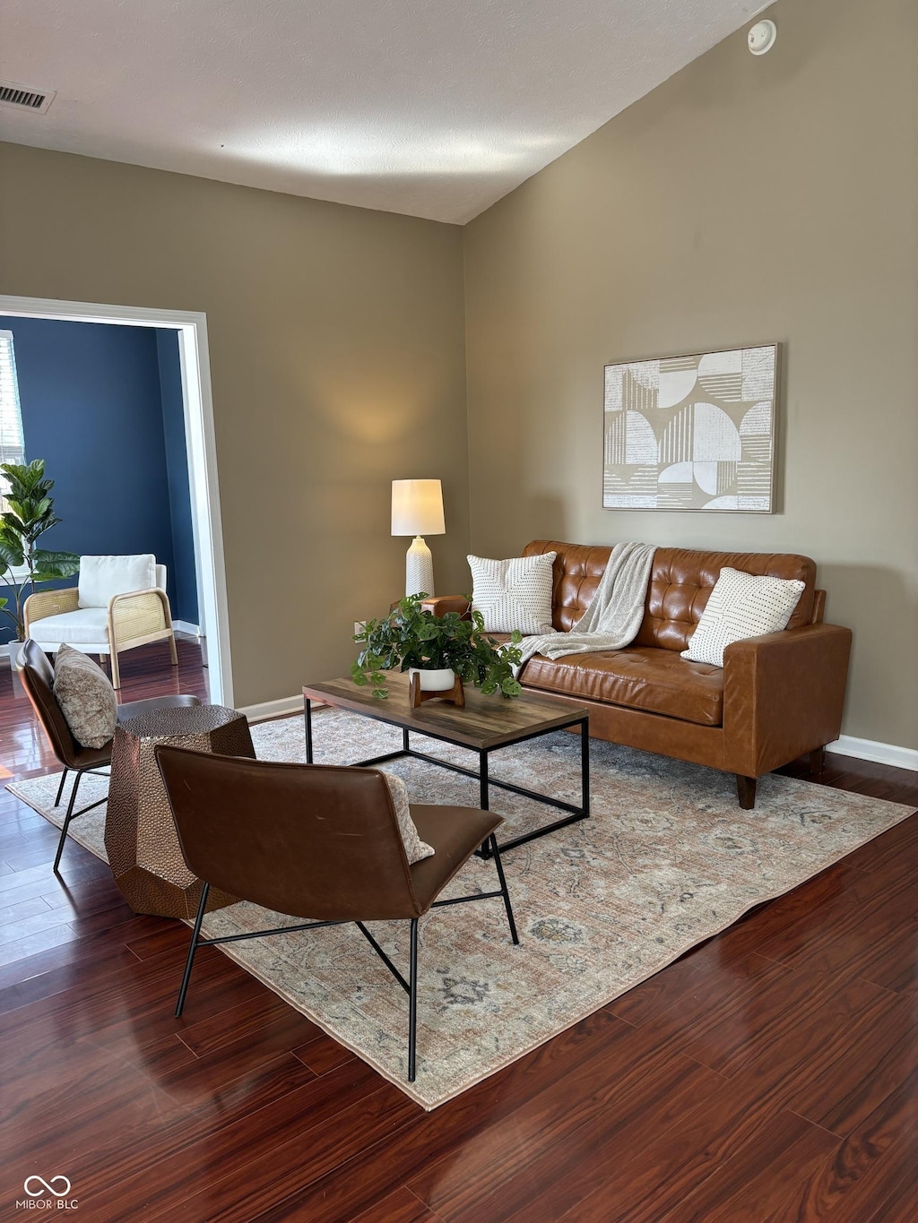 living room with wood finished floors, visible vents, and baseboards