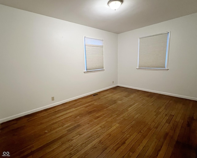 unfurnished room with dark wood-style floors, baseboards, and visible vents