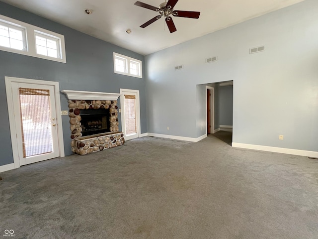 unfurnished living room with carpet floors, a stone fireplace, and visible vents