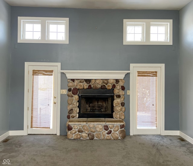 unfurnished living room with baseboards, carpet flooring, plenty of natural light, and a fireplace