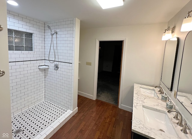 full bathroom featuring tiled shower, a sink, baseboards, and wood finished floors