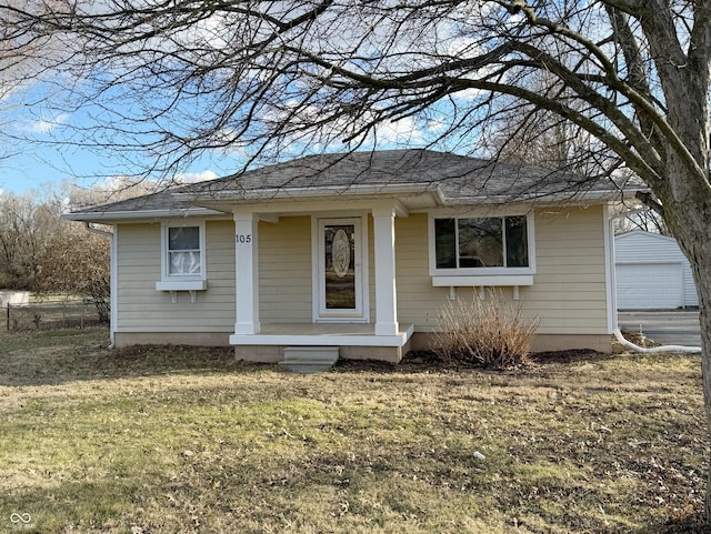 view of front of house featuring a shingled roof, a front lawn, an outdoor structure, and fence