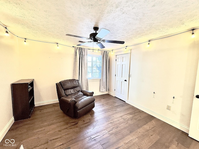 living area with hardwood / wood-style flooring, ceiling fan, and a textured ceiling