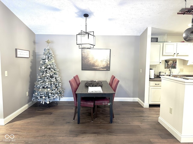 dining space featuring dark hardwood / wood-style flooring, a textured ceiling, and an inviting chandelier