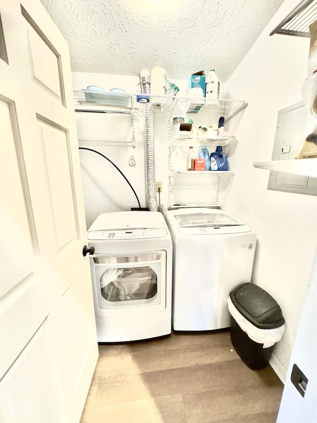 washroom with washing machine and dryer, laundry area, a textured ceiling, and wood finished floors