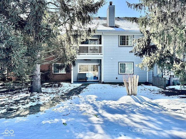 snow covered property with a chimney and a balcony