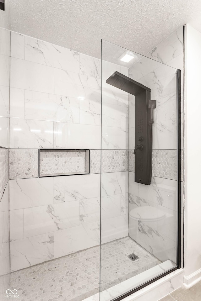 bathroom featuring a tile shower and a textured ceiling