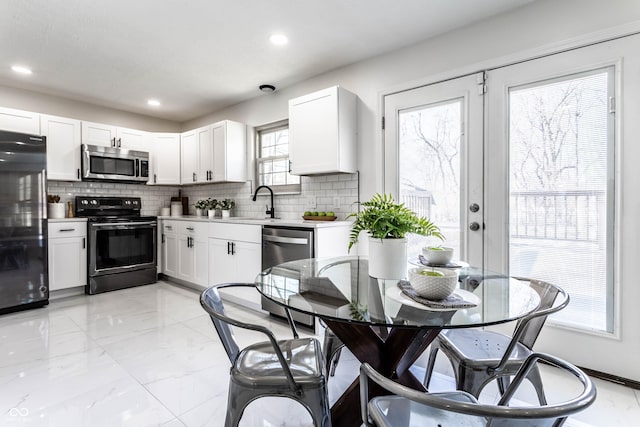 kitchen with appliances with stainless steel finishes, white cabinetry, sink, backsplash, and french doors