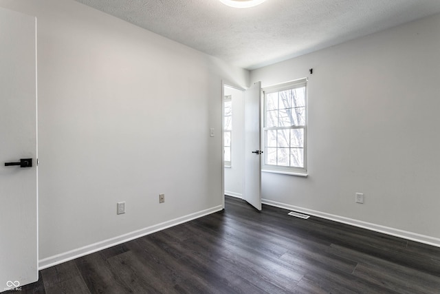 spare room featuring dark hardwood / wood-style flooring and a textured ceiling