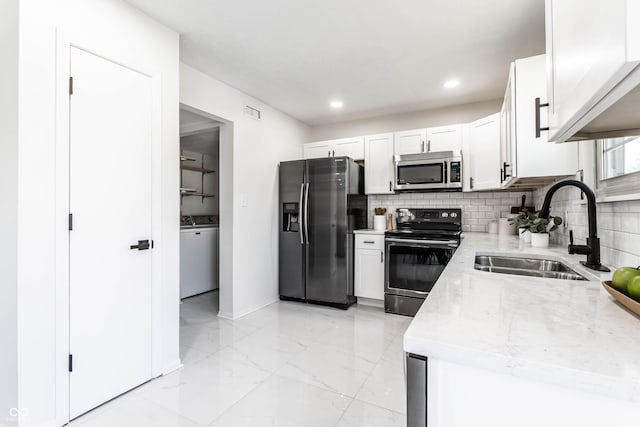 kitchen with sink, white cabinets, decorative backsplash, stainless steel appliances, and light stone countertops