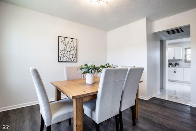 dining room featuring dark hardwood / wood-style flooring and a textured ceiling