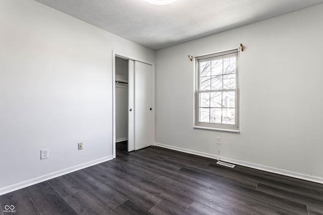 unfurnished bedroom with dark wood-type flooring, a closet, and a textured ceiling