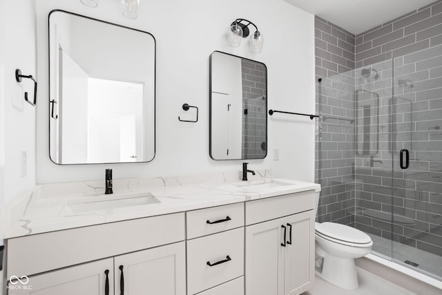 bathroom featuring a shower with shower door, toilet, and vanity