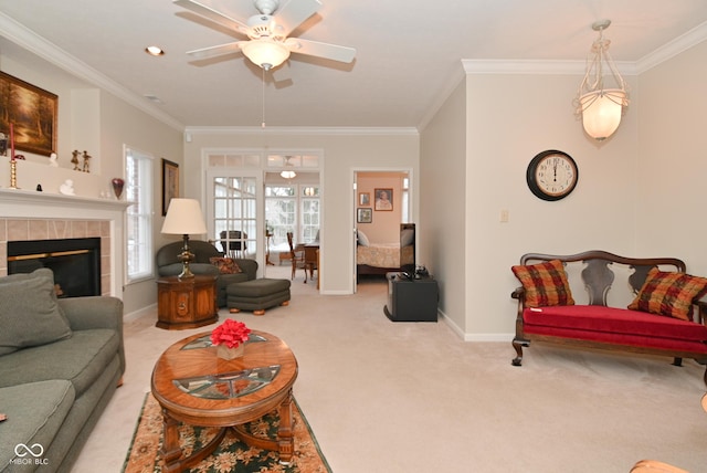 living room featuring ceiling fan, ornamental molding, a tile fireplace, and light carpet