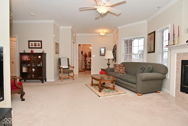 living room with a tiled fireplace, ornamental molding, light colored carpet, and ceiling fan