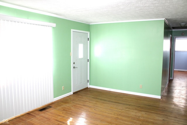 unfurnished room with a textured ceiling, dark hardwood / wood-style flooring, and ornamental molding