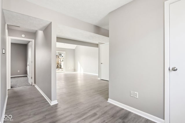 corridor with hardwood / wood-style floors, a textured ceiling, and lofted ceiling