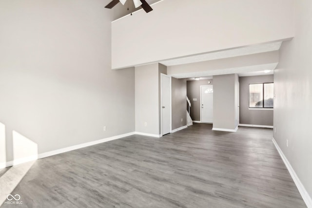 unfurnished living room with dark wood-type flooring and ceiling fan