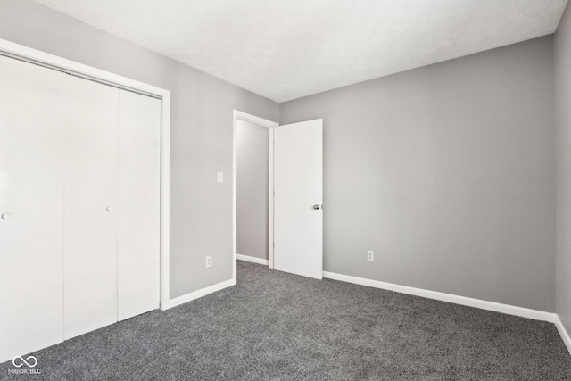 unfurnished bedroom with dark carpet and a closet