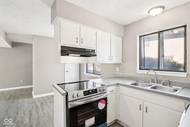 kitchen with kitchen peninsula, sink, white cabinetry, stainless steel range with electric stovetop, and a textured ceiling