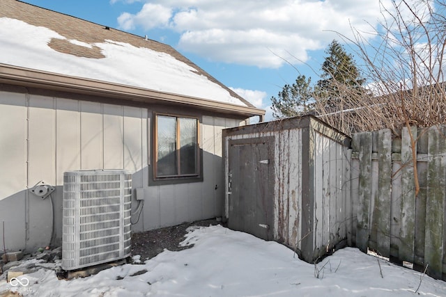 view of snowy exterior featuring cooling unit and a storage shed