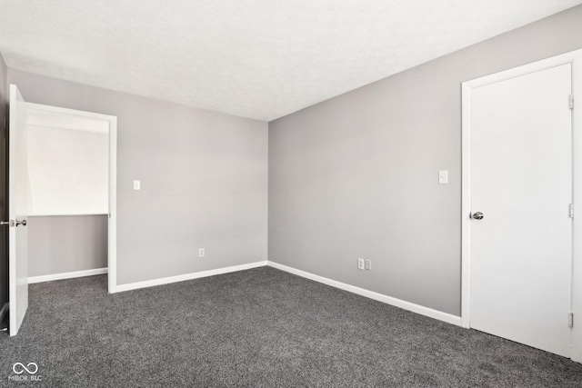 empty room with dark colored carpet and a textured ceiling