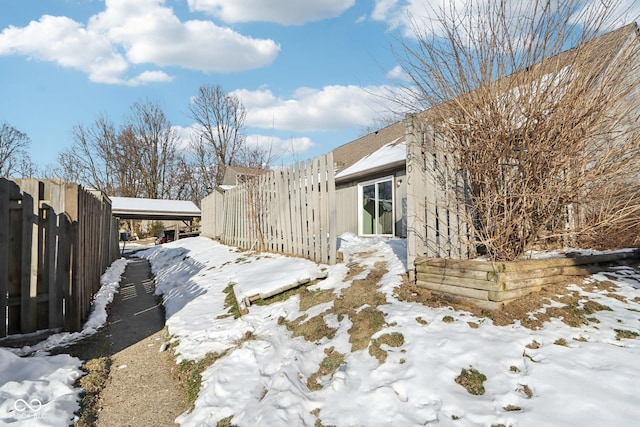 yard layered in snow featuring a carport