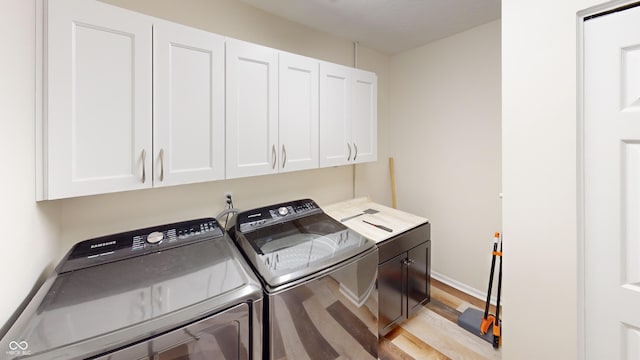 washroom with cabinets, washer and dryer, and light hardwood / wood-style floors