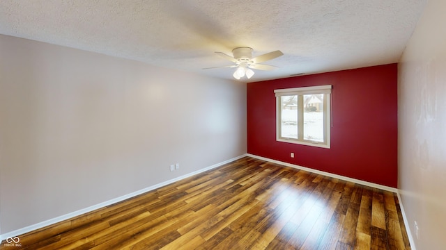 spare room with ceiling fan, dark wood-type flooring, and a textured ceiling