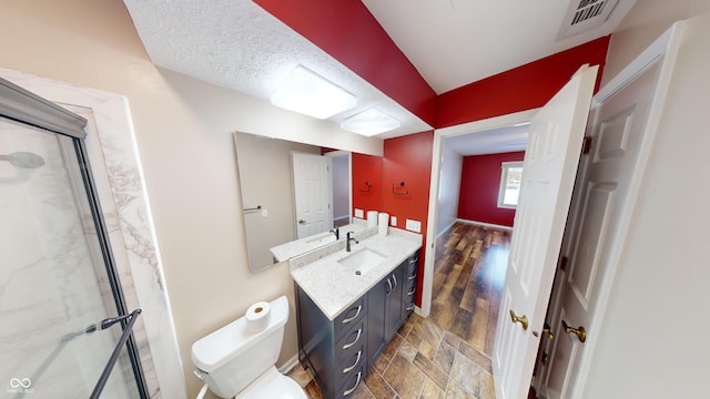 bathroom with vanity, an enclosed shower, a textured ceiling, and toilet