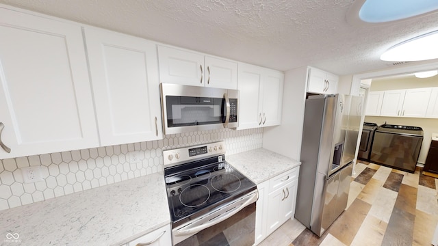 kitchen with white cabinets, decorative backsplash, stainless steel appliances, light stone countertops, and washer and clothes dryer