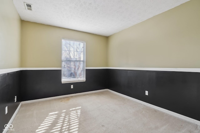 spare room with a textured ceiling and light colored carpet