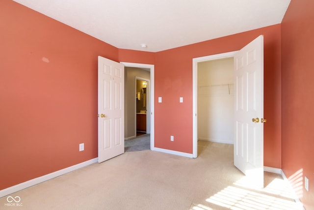 unfurnished bedroom featuring a closet, a spacious closet, and light colored carpet