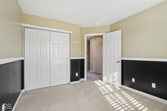 unfurnished bedroom featuring a closet and light carpet