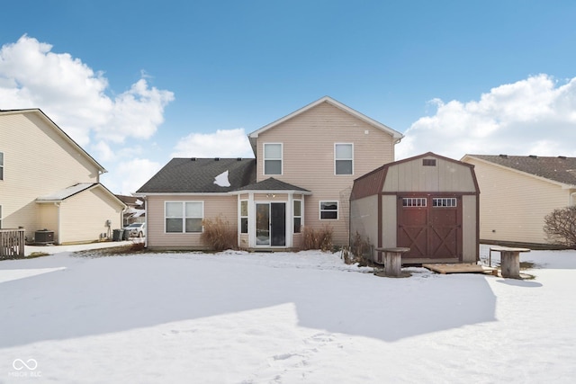 snow covered house with a storage unit and central air condition unit