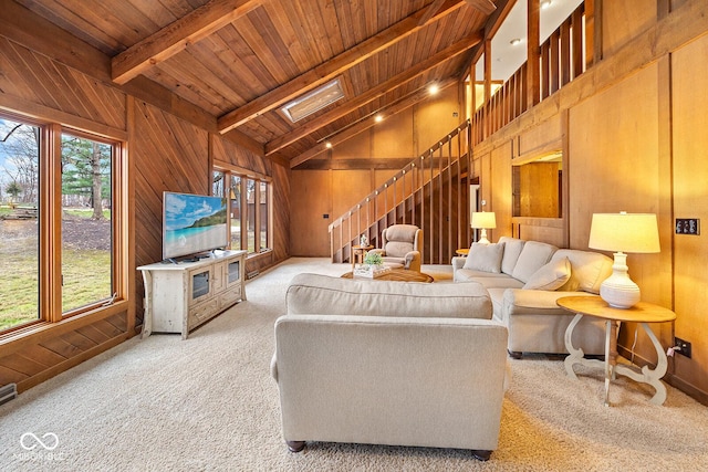 carpeted living room with beamed ceiling, wooden walls, high vaulted ceiling, and wooden ceiling