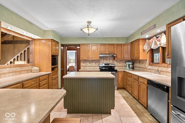 kitchen with sink, backsplash, a center island, stainless steel appliances, and a textured ceiling