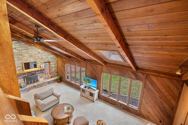 unfurnished living room with wood ceiling, a brick fireplace, wooden walls, vaulted ceiling with skylight, and carpet