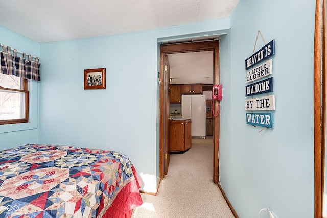 bedroom featuring freestanding refrigerator, light colored carpet, and baseboards