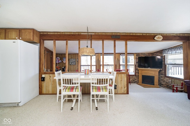 carpeted dining room with brick wall and a fireplace