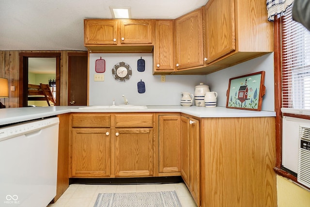 kitchen with light tile patterned floors, light countertops, white dishwasher, and a sink