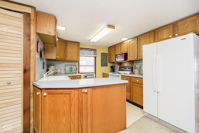 kitchen featuring white appliances, brown cabinetry, a peninsula, light countertops, and a sink