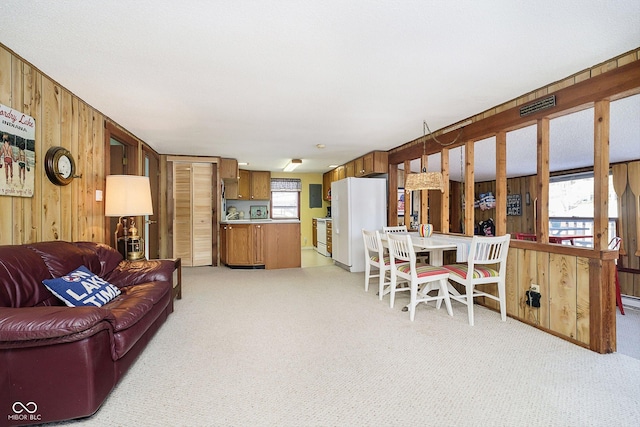 living area featuring visible vents, light carpet, and wooden walls