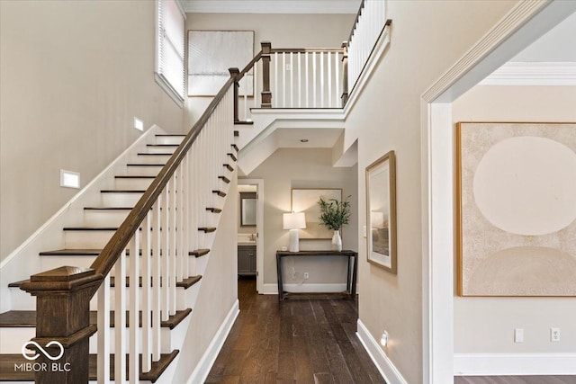 staircase featuring a high ceiling, wood finished floors, and baseboards